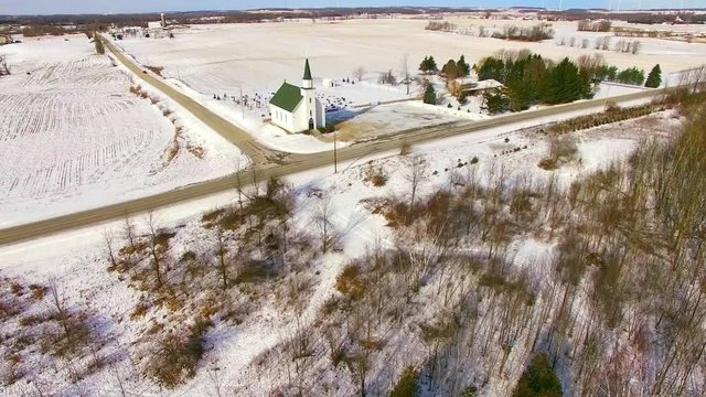 Little white iconic church with cemetery on a snowy rural landscape.
