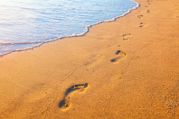 beach, wave and footprints at sunset time