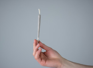 Mann h&auml;lt einen gerollten Joint in der Hand