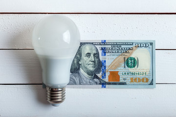 led bulb with money on table.