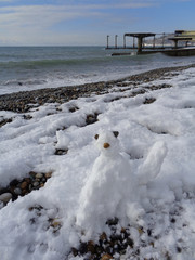 Funny little snowman on winter beach