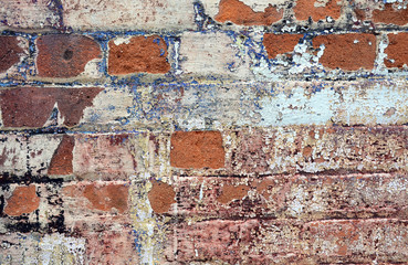 Old cracked rendered wall from historic building with exposed brick and mortar and peeling paint. Grunge vintage texture background.