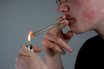 Mann hält einen Joint in der Hand und zündet ihn mit dem Feuerzeug an