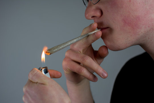 Mann h&auml;lt einen Joint in der Hand und z&uuml;ndet ihn mit dem Feuerzeug an