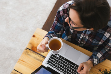 Caucasian woman sitting in front of her laptop and holding a cup