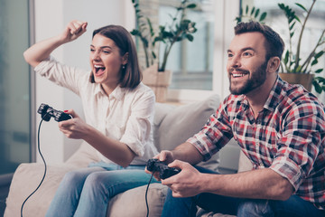 Two excited happy lovers playing video game