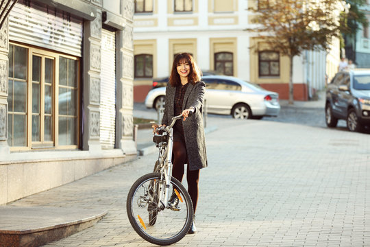 Pretty young woman with bicycle outdoors