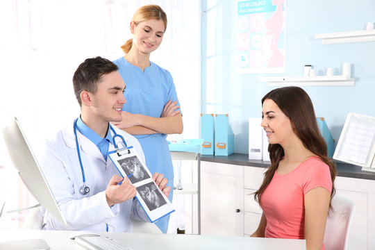 Doctor showing baby ultrasound image to pregnant woman