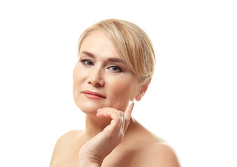 Mature woman applying anti-aging cream onto face, on white background