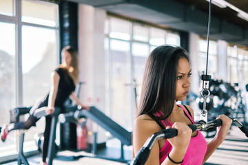 Fototapeta premium Beautiful young fitness girl in gym. doing lat machine exercises