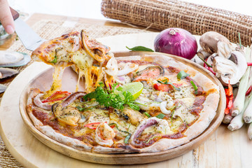 Delicious Seafood Pizza on a wooden table with ingredients aroun