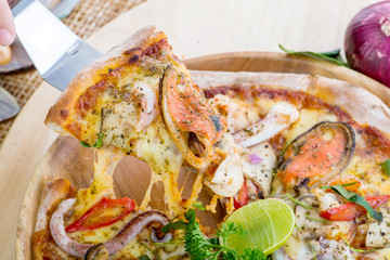 Delicious Seafood Pizza on a wooden table with ingredients aroun