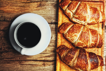 Coffee and croissant on wooden background