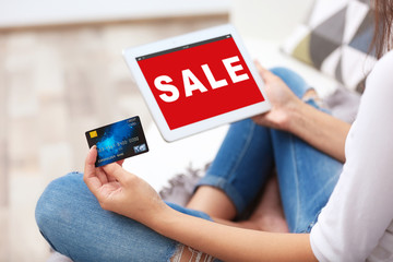 Sale concept. Woman using tablet and credit card for internet online shopping at home