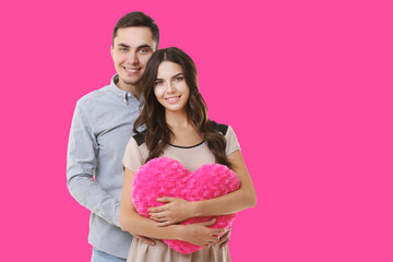 Young couple with heart posing on color background