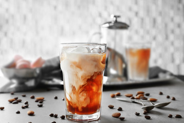 Glass of cold coffee with beans and nuts on table
