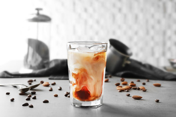 Glass of cold coffee with beans and nuts on table