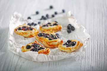 Sweet tasty pastries on craft paper against wooden background