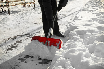 Man removing snow with red shovel