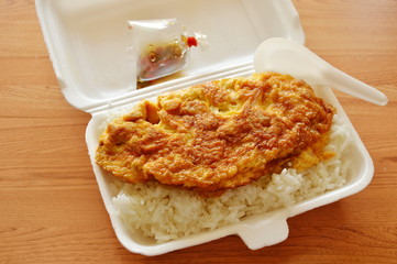 omelet on rice in foam box with plastic spoon ready for eat