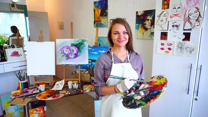 Schoolgirl of Art School Looks at Camera and on Palette, Smiles and Located Among Studio For Drawing That Walls in Pictures.
