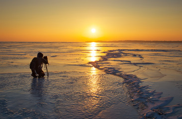 Obraz premium Photographer take pictures on the ice during sunset