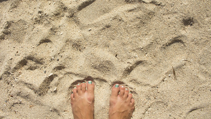 White sand beach and female feet. Soft sand beach top view photo for background or template