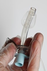 Tracheotomy tube with polyuretane conical cuff viewed from bottom side, held in hand in transparent...
