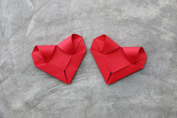 couple folding red paper hearts on cement wall for valentine pat