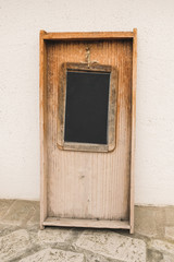Fototapeta na wymiar Copy space black chalkboard inside wooden frame leaning on white wall