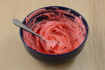 Mixing more red food dye into red frosting in blue table to deepen color
