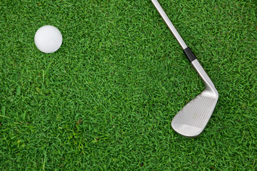 iron golf club and ball on a green grass