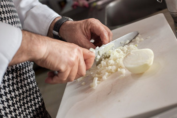 Obraz na płótnie Canvas Chef cutting onion cubes on white board