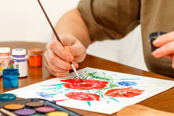Naklejka premium Woman's hand painting poppy flowers
