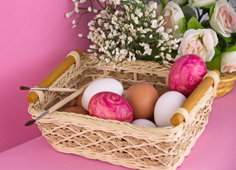 Fototapeta na wymiar пасхальные яйца в корзинке на розовом фоне 