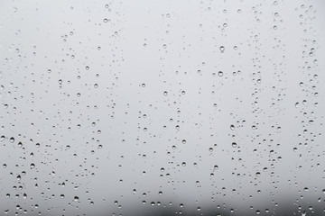 Rain water droplets on glass window with gloomy sky