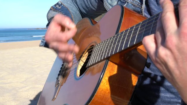 Closeup of man playing the guitar on the beach