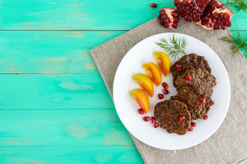 Juicy liver cutlets with pomegranate seeds on a white plate. The top view.