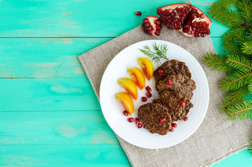 Juicy liver cutlets with pomegranate seeds on a white plate. The top view.