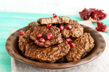 Juicy liver cutlets with pomegranate seeds on a ceramic plate.