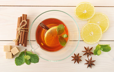 tea in a transparent mug with lemon and cinnamon and mint leaves