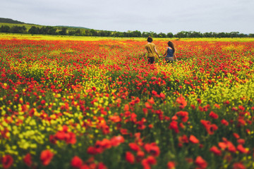 Young happy couple with curly hair enjoying in bright red and yellow field
