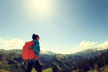 young woman backpacker hiking on forest mountain peak