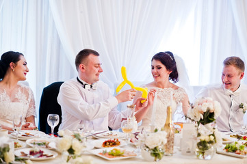 Wedding couple with bridesmaids and best man sitting at table on