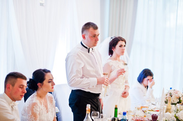 Wedding couple with bridesmaids and best man sitting at table on
