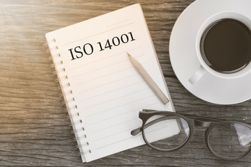 Concept ISO 14001 message on notebook with glasses, pencil and c