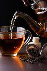 cup of tea with teapot on dark background