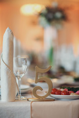 glasses,white napkins and number five stand on the wedding table