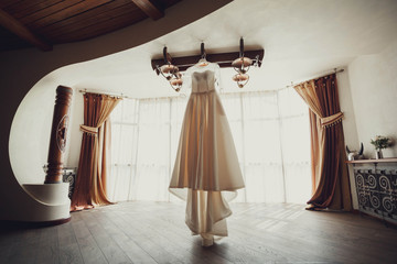 beautiful white dress for the bride hanging on chandelier