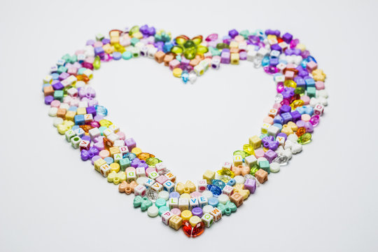 Colorful of beads with heart shape on white background.